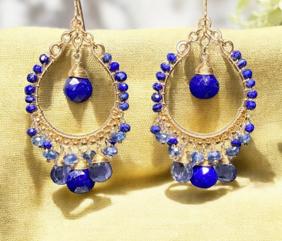 Gold hoop earrings with blue beads on a yellow fabric background