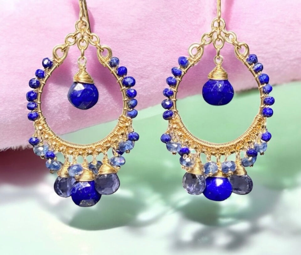 Gold hoop earrings with blue beads on a pink and green background