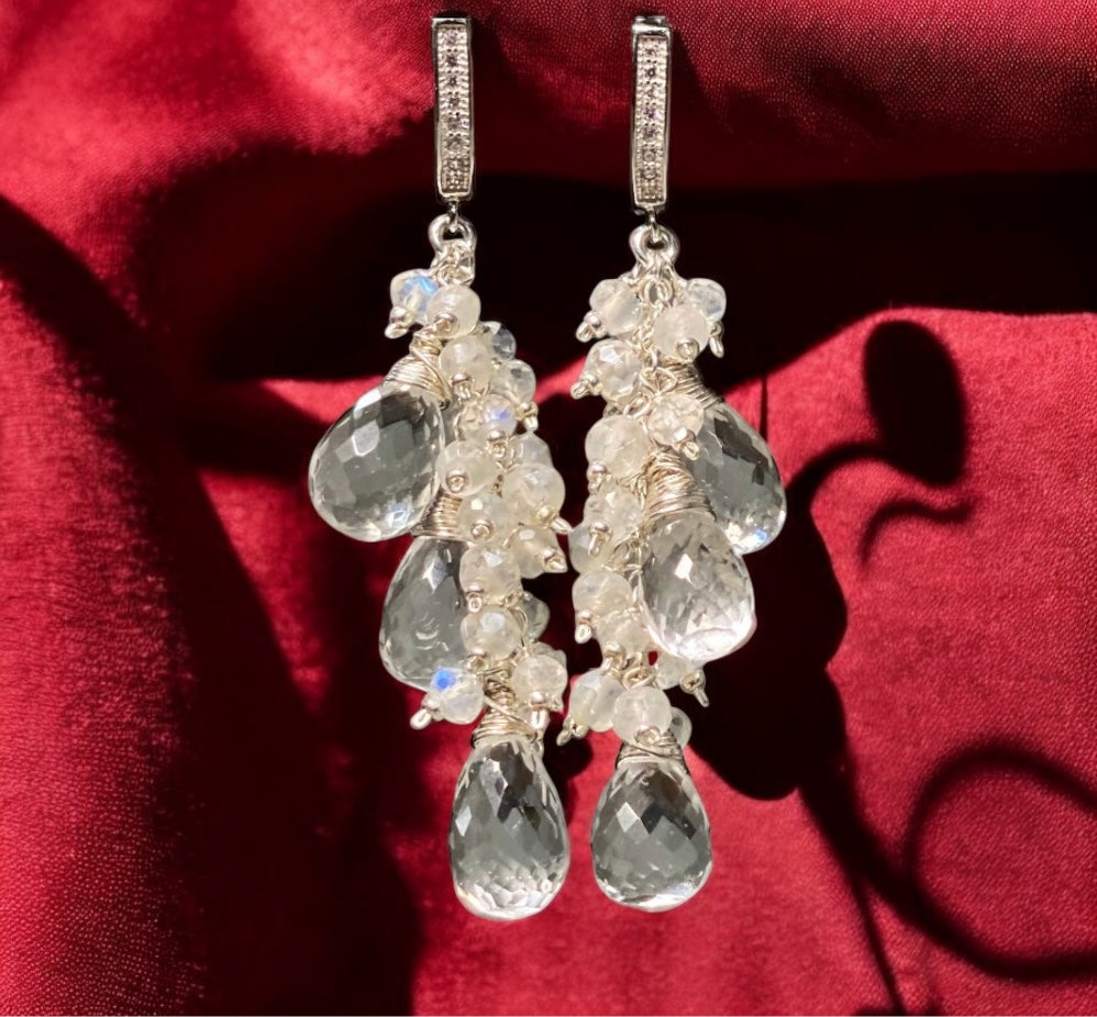 Delicate earrings with clear stones on a red fabric background