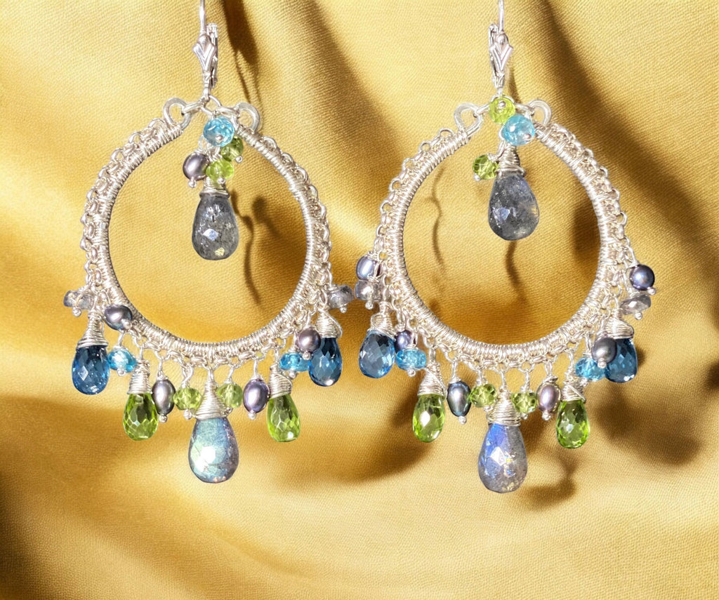 Elegant hoop earrings with gemstone drops on a gold fabric background