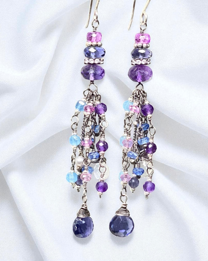 Pair of chandelier earrings with purple and blue beads on a white background