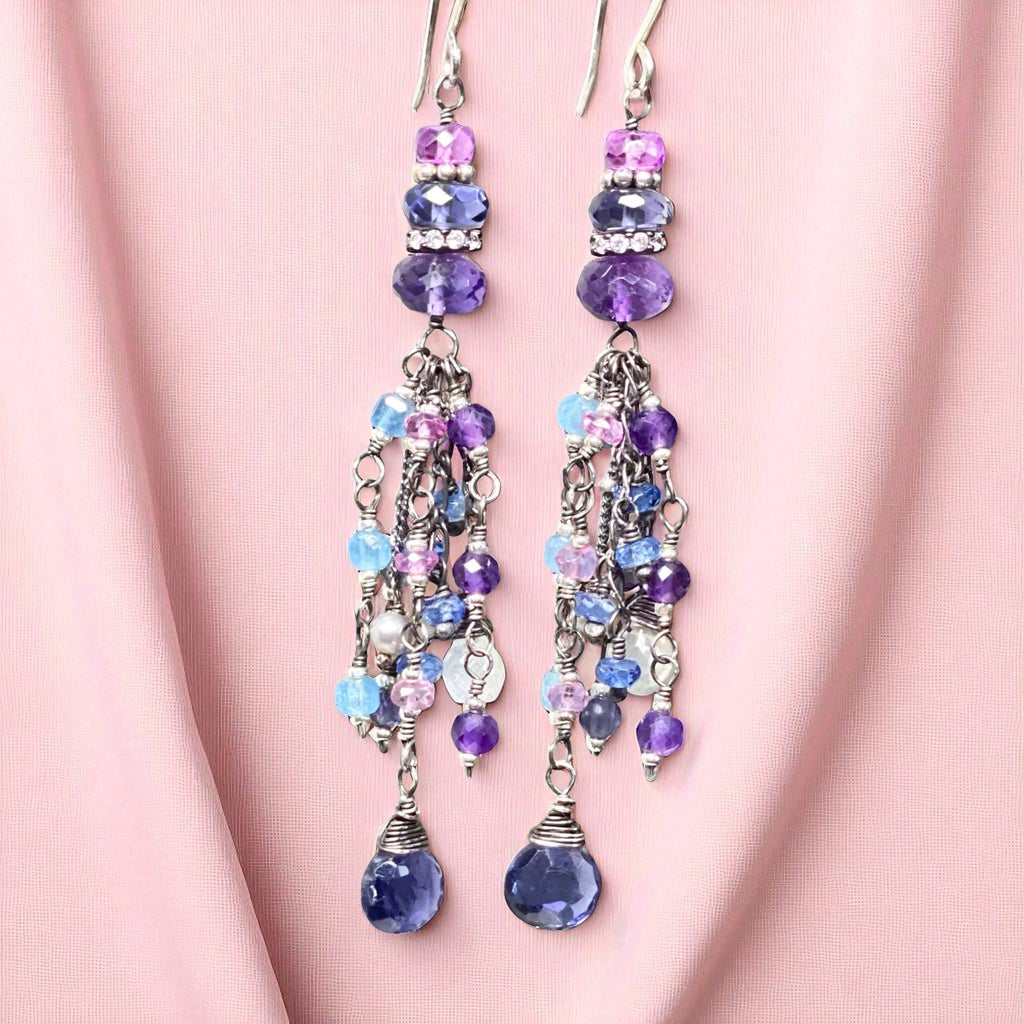 Beaded earrings with purple and blue beads on a pink fabric background