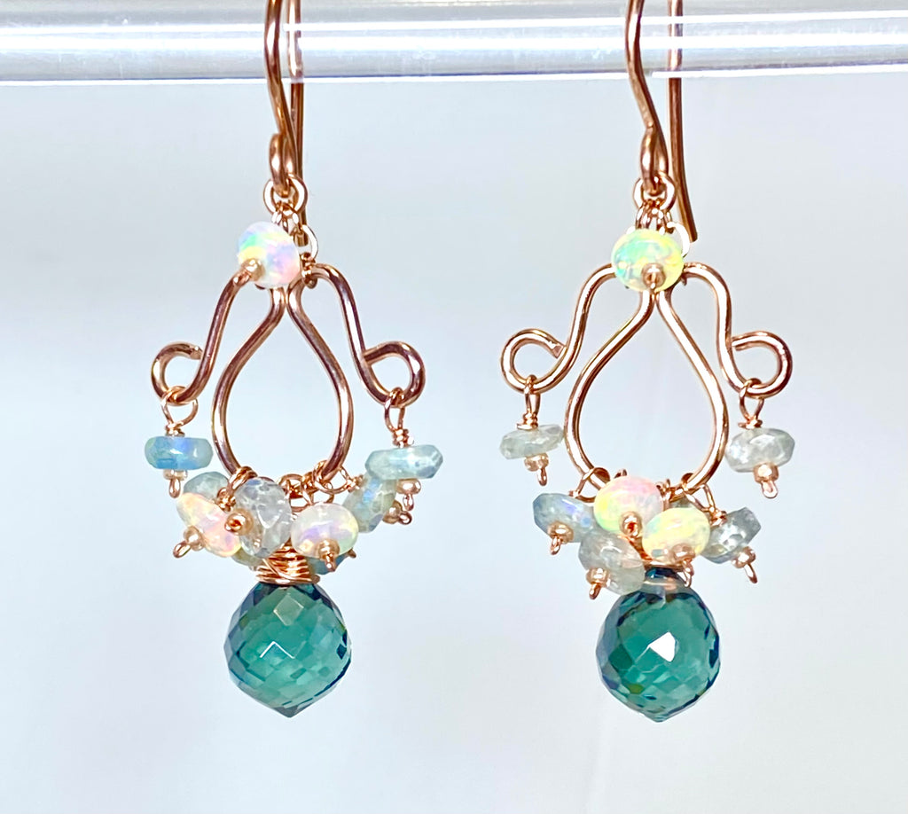 Opal aquamarine rose gold chandelier earrings dangling against white background