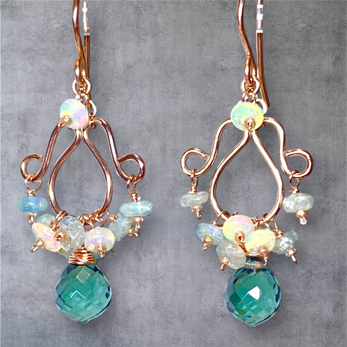 Rose gold chandelier earrings with moss aquamarine quartz, mystic aquamarine and Ethiopian opals against grey suede background
