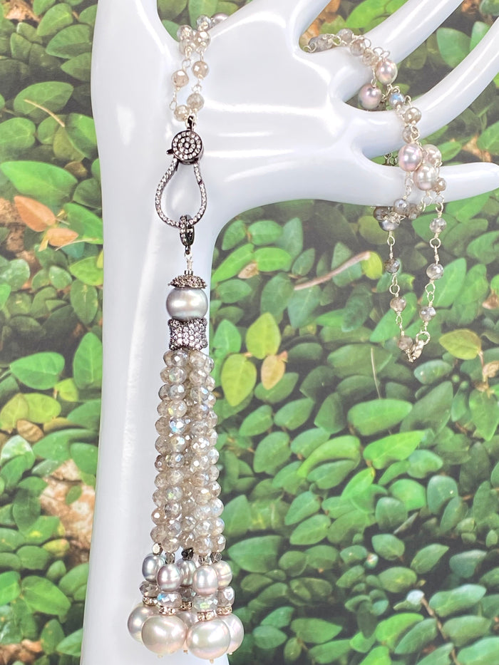 Mystic labradorite beaded tassel necklace draped over a white mannequin arm, showing the wire-wrapped oxidized sterling silver tassel and iridescent blue-green gemstone beads up close.