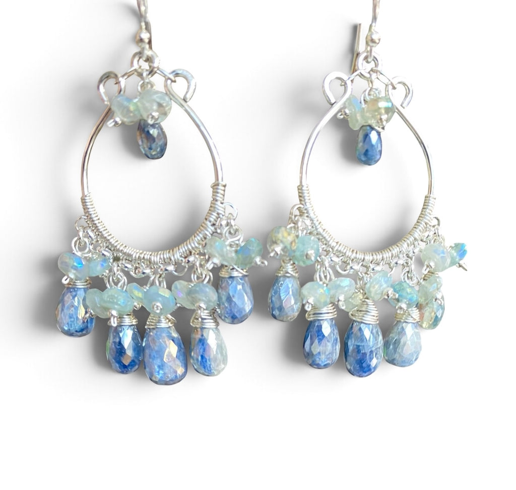 A pair of sterling silver hoop chandelier earrings with large open hoops, wrapped wire details, and multiple faceted blue and iridescent beads, shown on a plain white background.