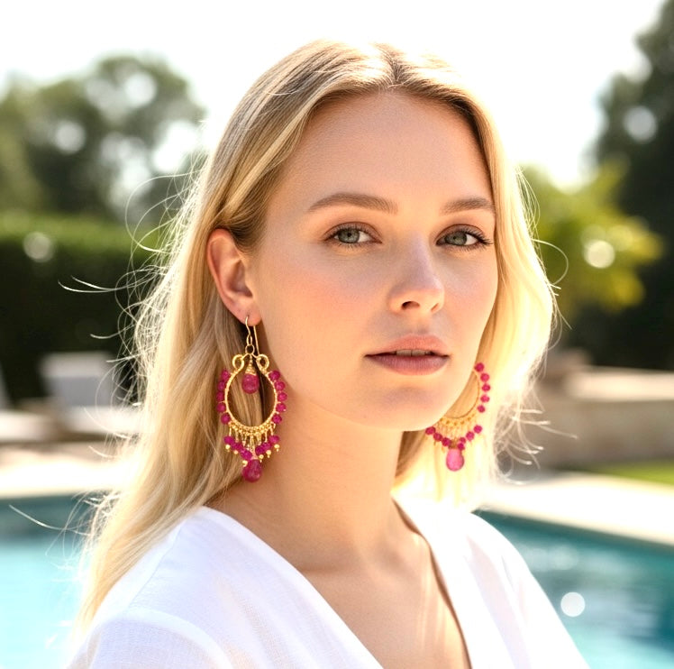 Red ruby pink sapphire gold chandelier hoop earrings on blonde model in white dress at resort pool