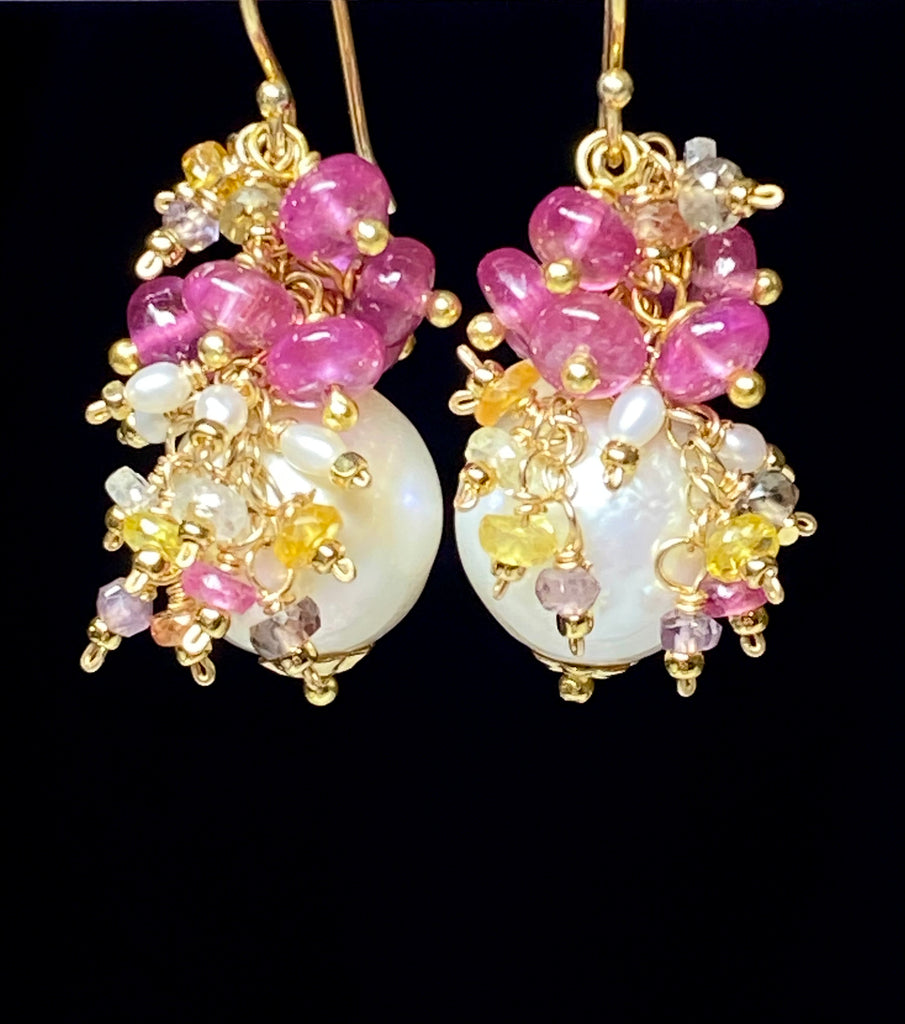 Pearl and pink sapphire cluster earrings gold dangling in front of black background showing movement