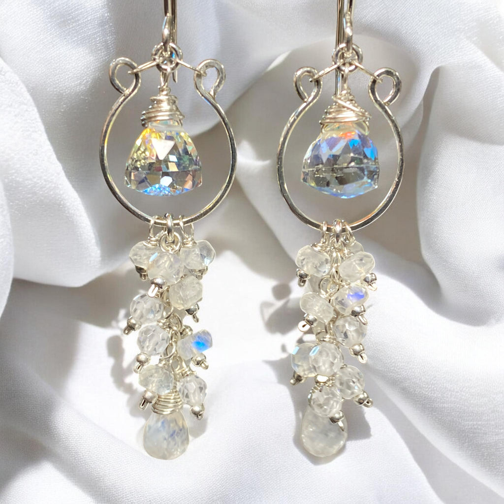 Pair of sterling silver chandelier earrings with rainbow quartz and rainbow moonstone gemstones on a white fabric background.