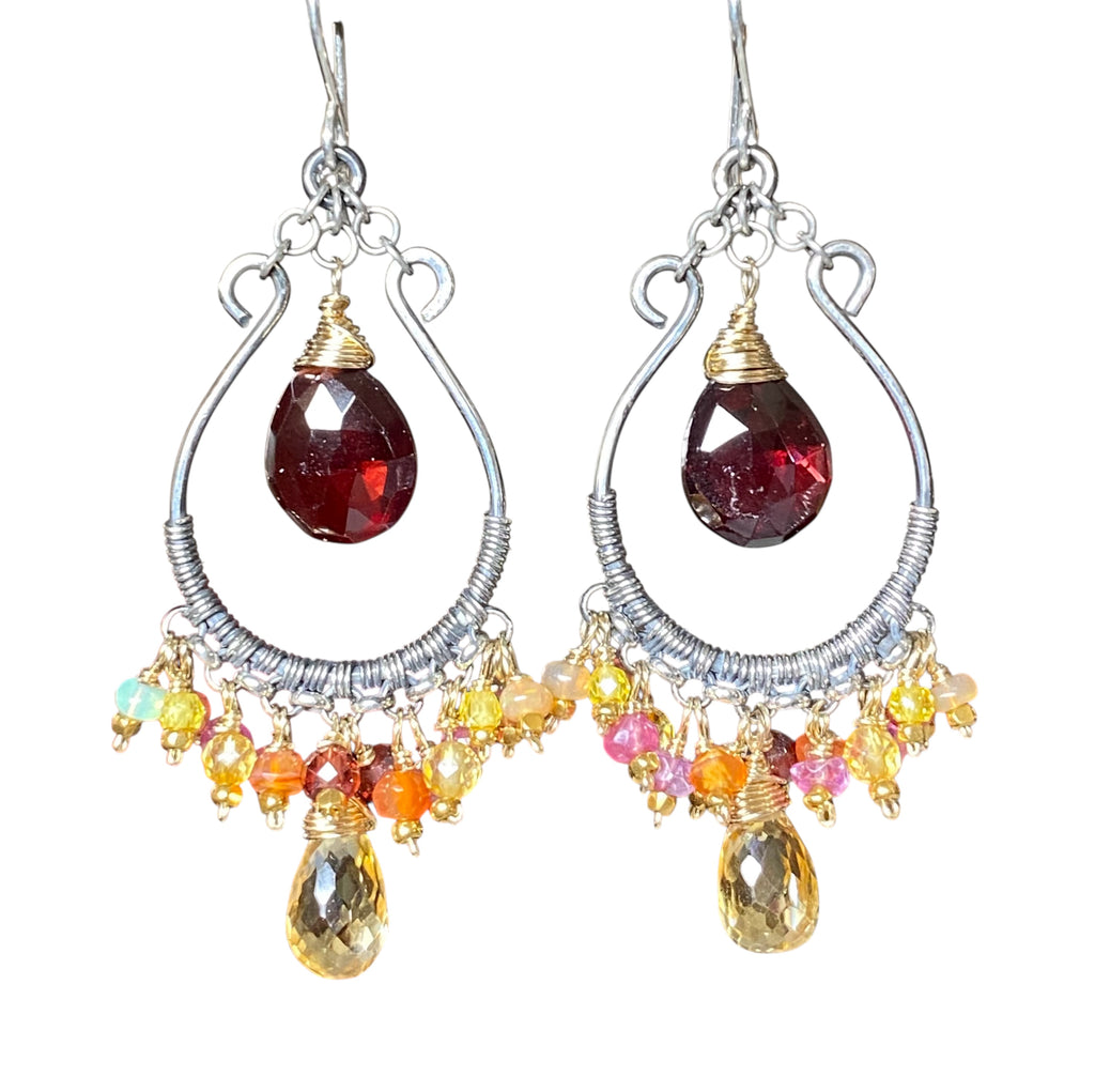 Red garnet and citrine mixed metal hoop earrings dangling against plain white background