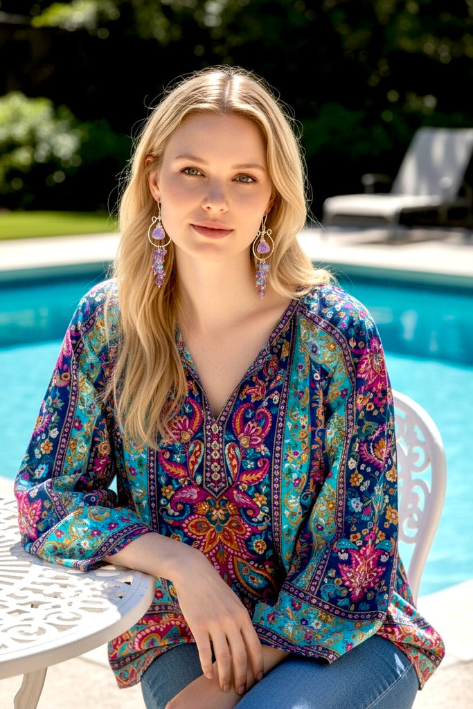 Model styling romantic lavender and pink amethyst statement chandelier hoop earrings, handmade in NY sitting in front of a resort pool.