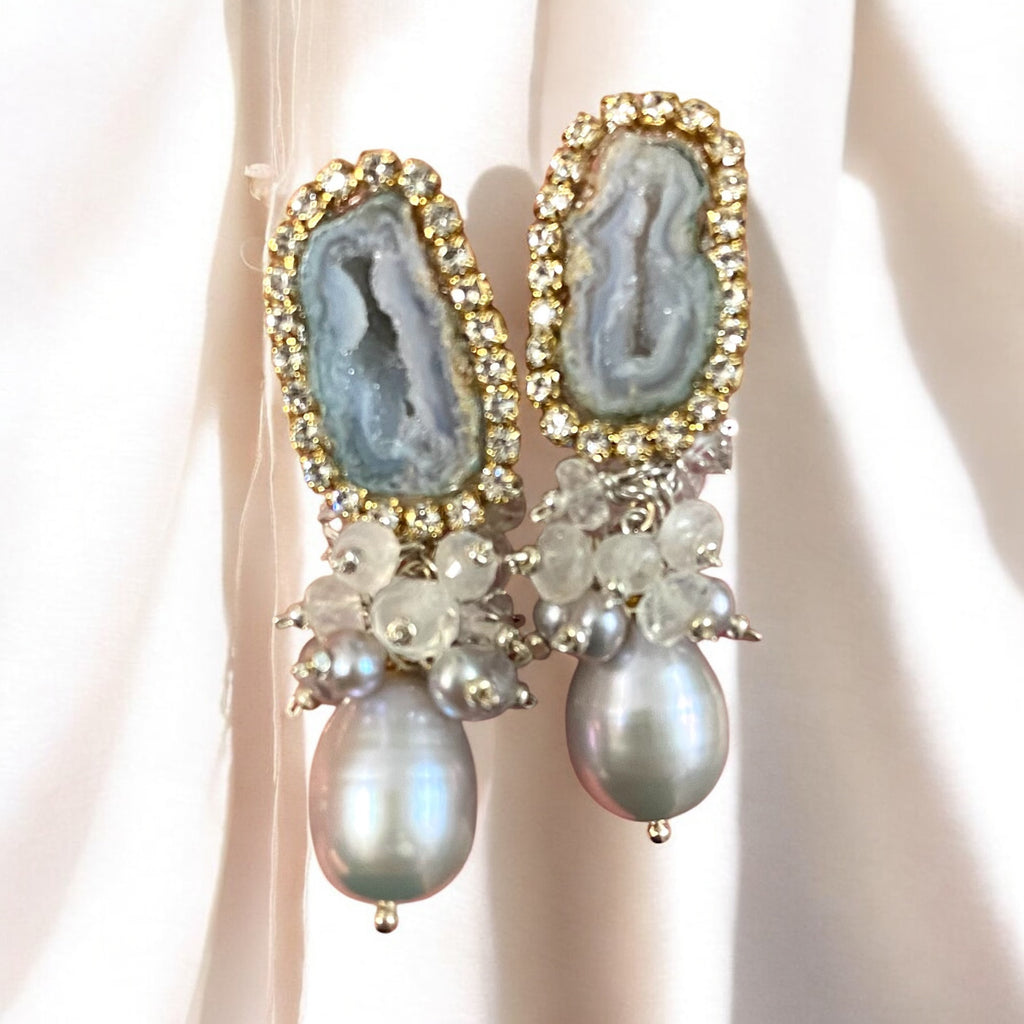 Elegant earrings with gemstones and pearls on a neutral background