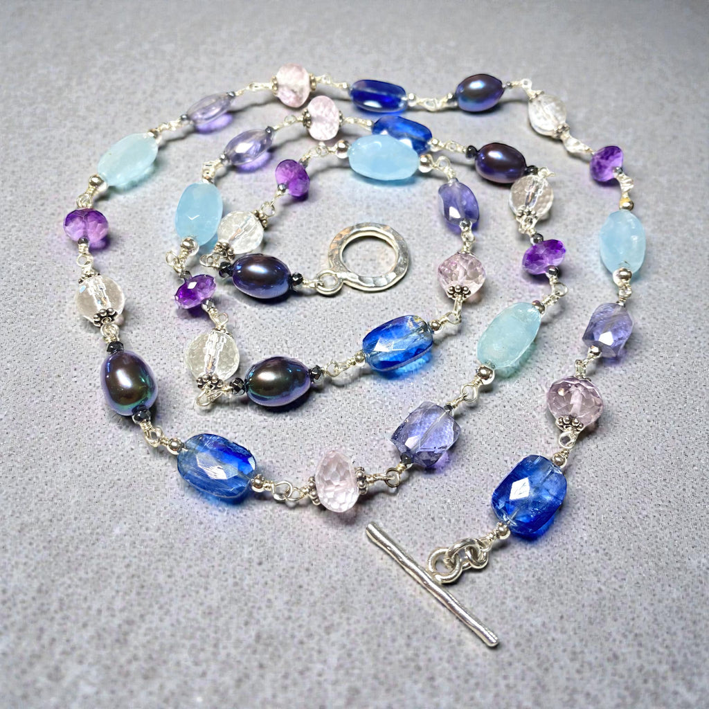 Blue purple gemstone peacock pearl long necklace sterling silver lying flat on grey background