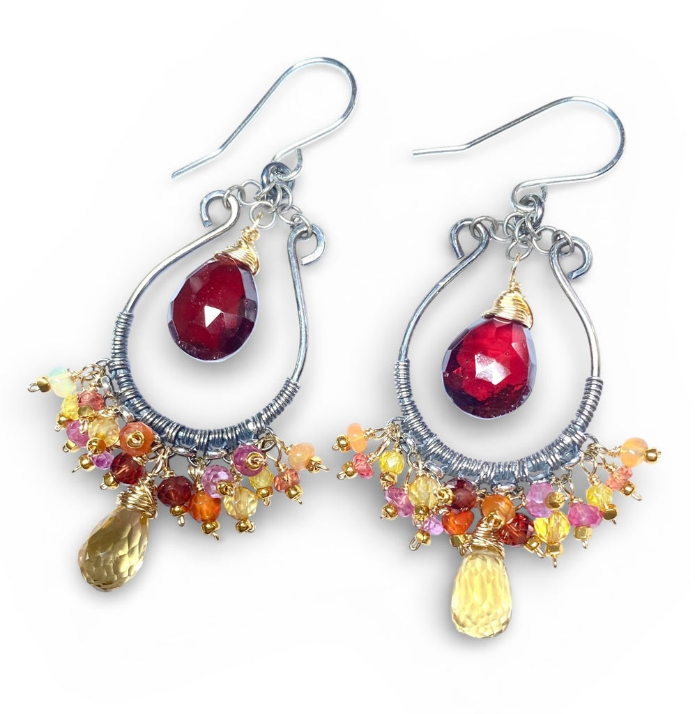 Garnet citrine mixed metal chandelier hoop earrings lying on plain white background