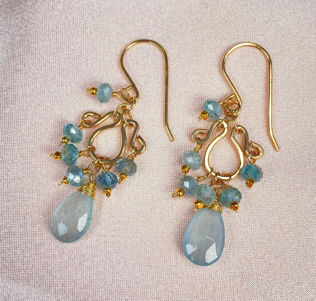 Close-up of petite gold-filled chandelier earrings on pale satin, showing French hooks, blue zircon beads and wire-wrapped moss aquamarine teardrops.