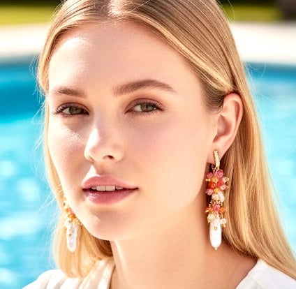 "Blonde woman wearing white Biwa pearl and coral hot pink cluster earrings with white dress, poolside headshot"