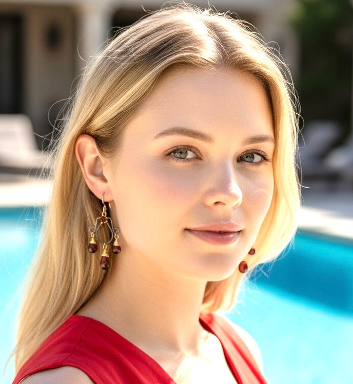 Oxidized silver chandelier earrings dangling red garnet faceted briolettes wire wrapped in 14kt gold fill wires shown on model headshot in front of pool Image