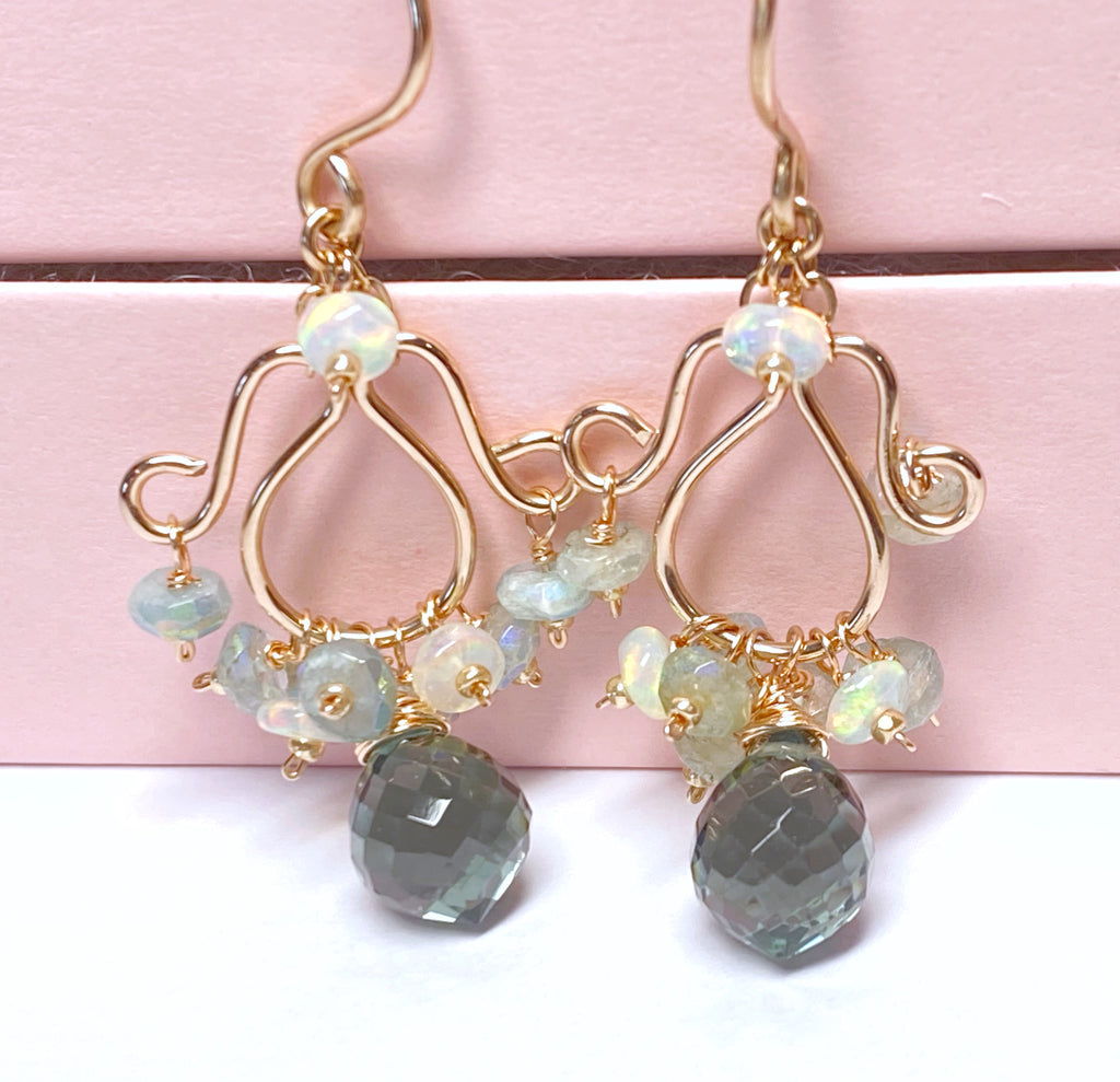 Rose gold chandelier earrings with moss aquamarine and Ethiopian opal dangling against pink jewelry box