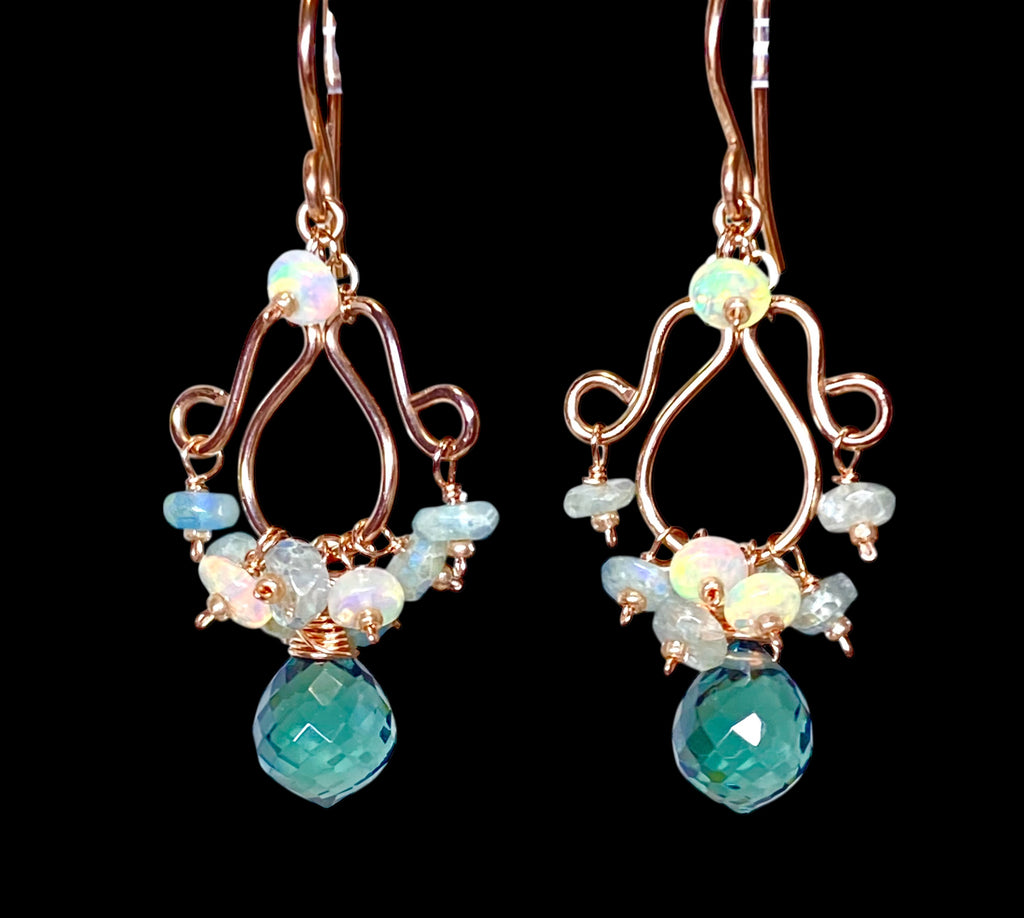 Rose gold chandelier earrings with opal and aquamarine dangling against black plain background