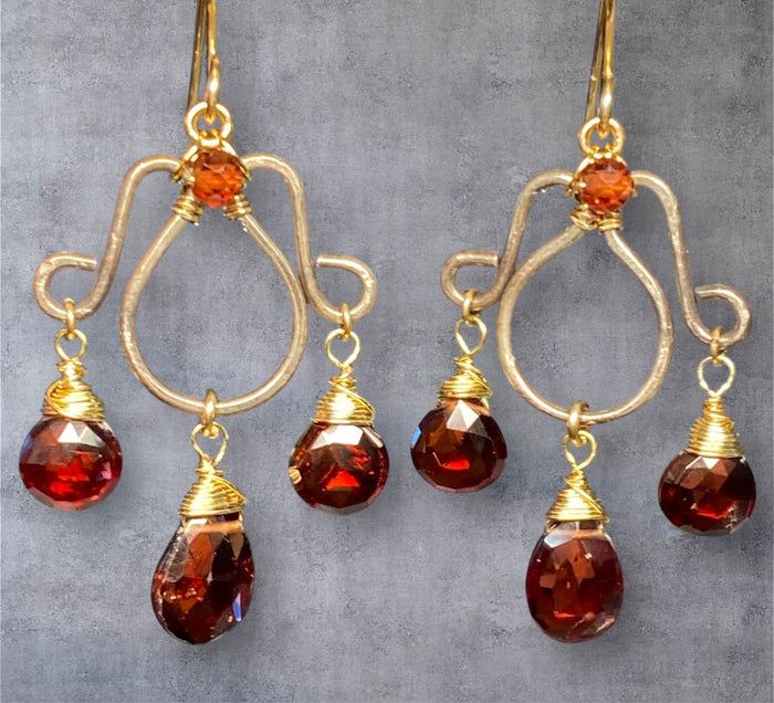 Oxidized silver chandelier earrings dangling red garnet faceted briolettes wire wrapped in 14kt gold fill wires on grey suede background 