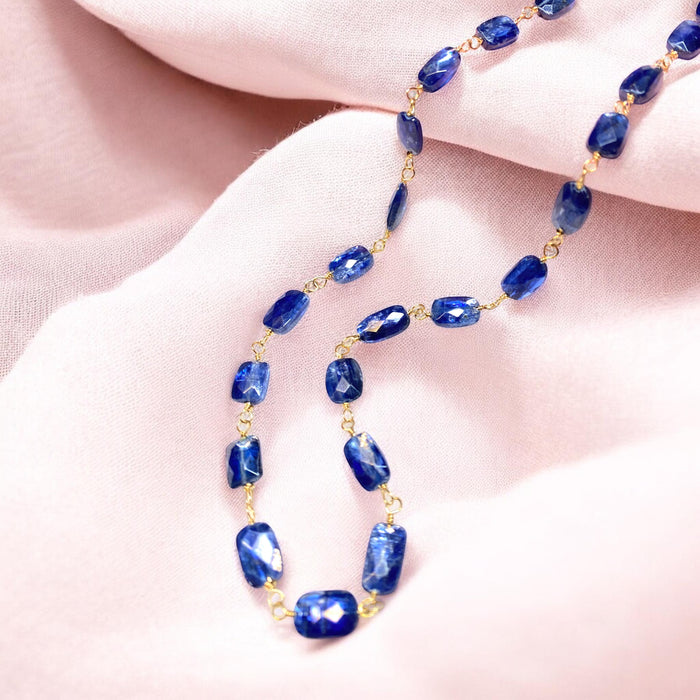 Blue kyanite wire wrapped necklace in 14kt gold fill draped on blush pink fabric showing royal blue gemstones
