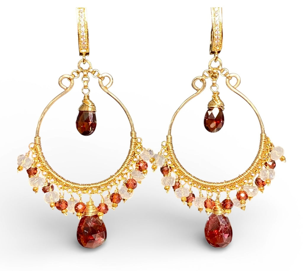 Gold filled chandelier hoop earrings with red garnet and moonstone standing against white background