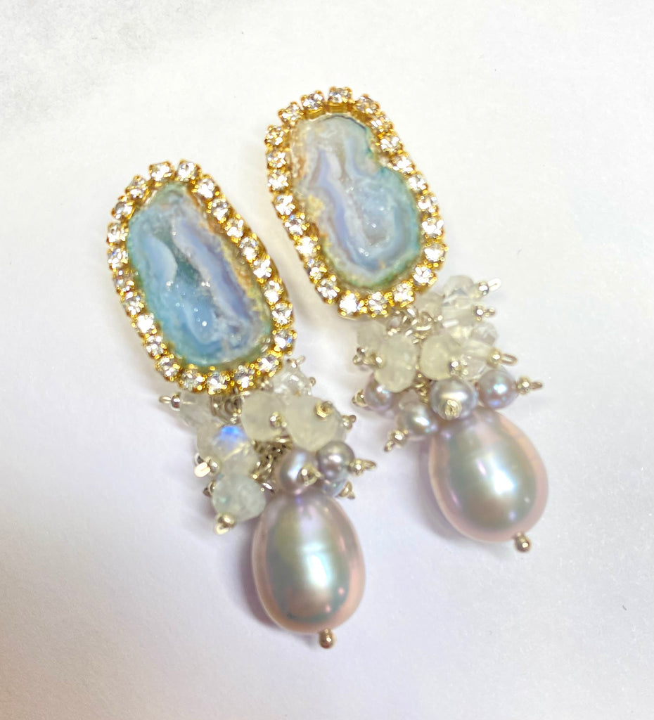 Elegant earrings withgeode druzy stones and pearls on a white background