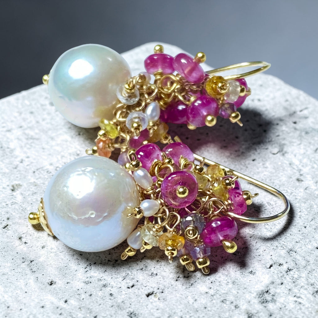 Pearl and pink sapphire cluster earrings gold lying on grey granite slab - flat lay product shot