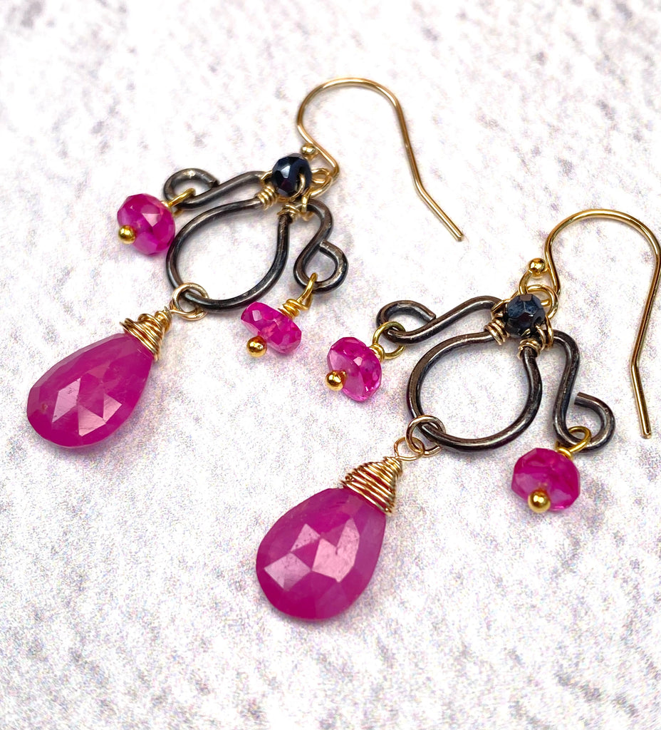 Angled view of pink sapphire earrings showing dark gunmetal sterling silver frames, gold-filled French hooks and fuchsia rondelles on gold vermeil headpins.