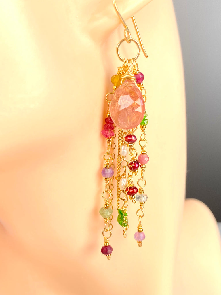 Close-up of a pink tourmaline dangle earring on a display ear, showing the faceted pink briolette and cascading gold-filled chains with gemstones and freshwater pearls.
