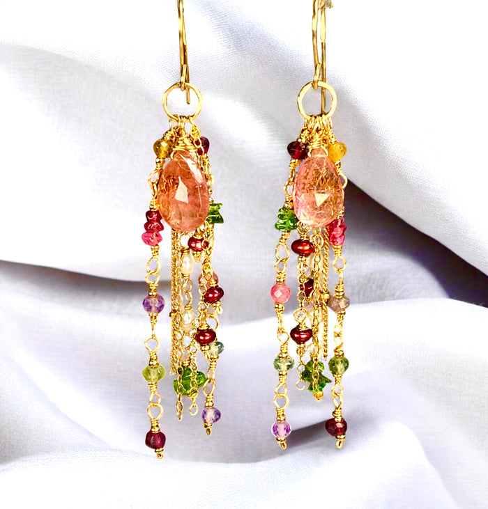 Pink tourmaline long dangle earrings in 14kt gold fill, hanging against white fabric with cascading multicolor gemstones and white and cranberry freshwater pearls.
