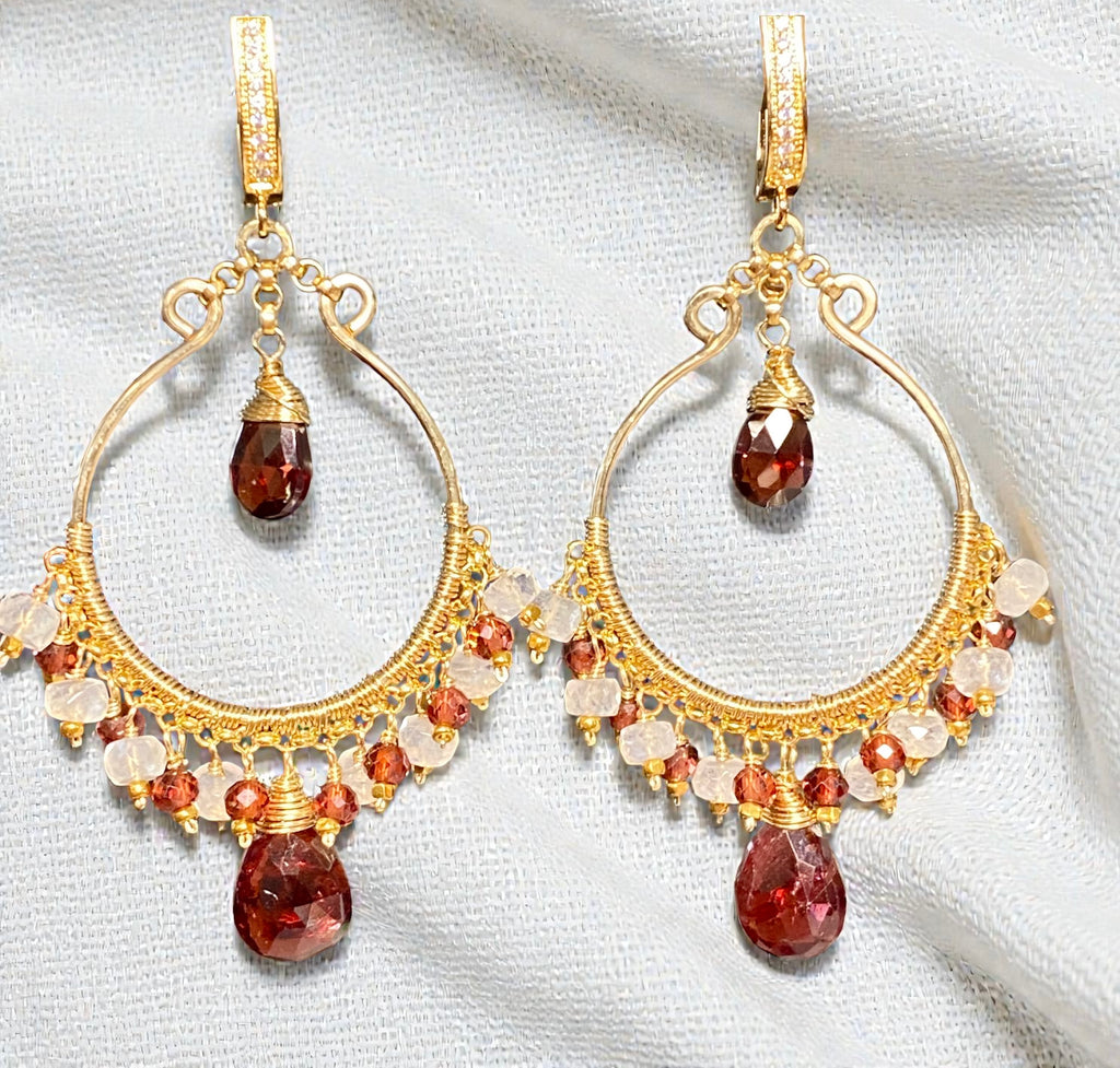Red garnet gold hoop earrings with rainbow moonstone on white linen background