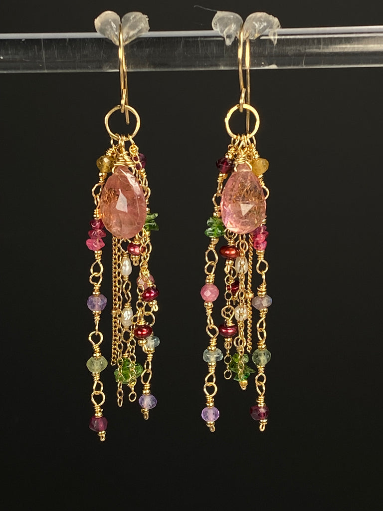 Pair of pink tourmaline earrings suspended from a clear display bar against a dark background, showing gold-filled French hooks and long gemstone chain dangles.