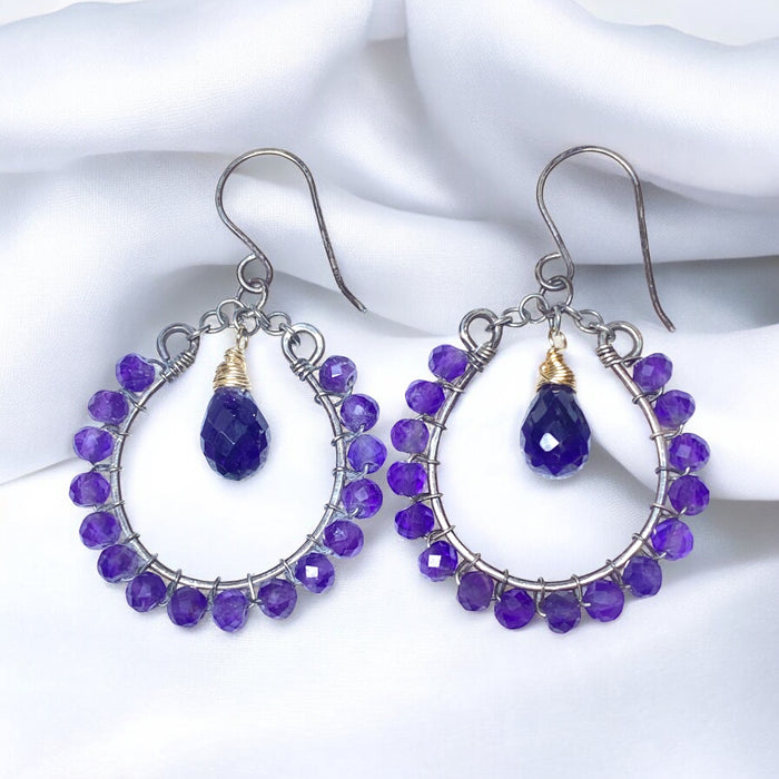 Purple amethyst chandelier hoop earrings mixed metals resting against draped white fabric