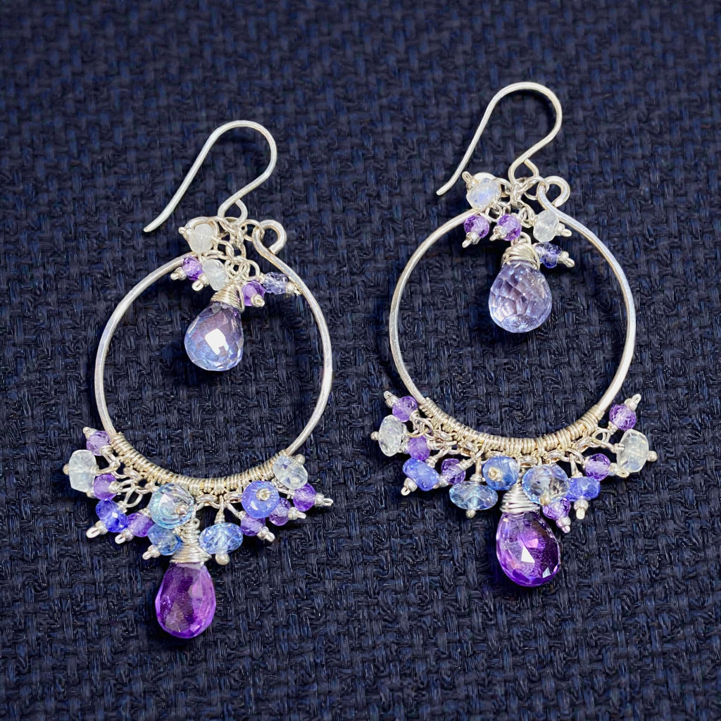 Colorful gemstone chandelier earrings amethyst tanzanite blue violet quartz lying on black background
