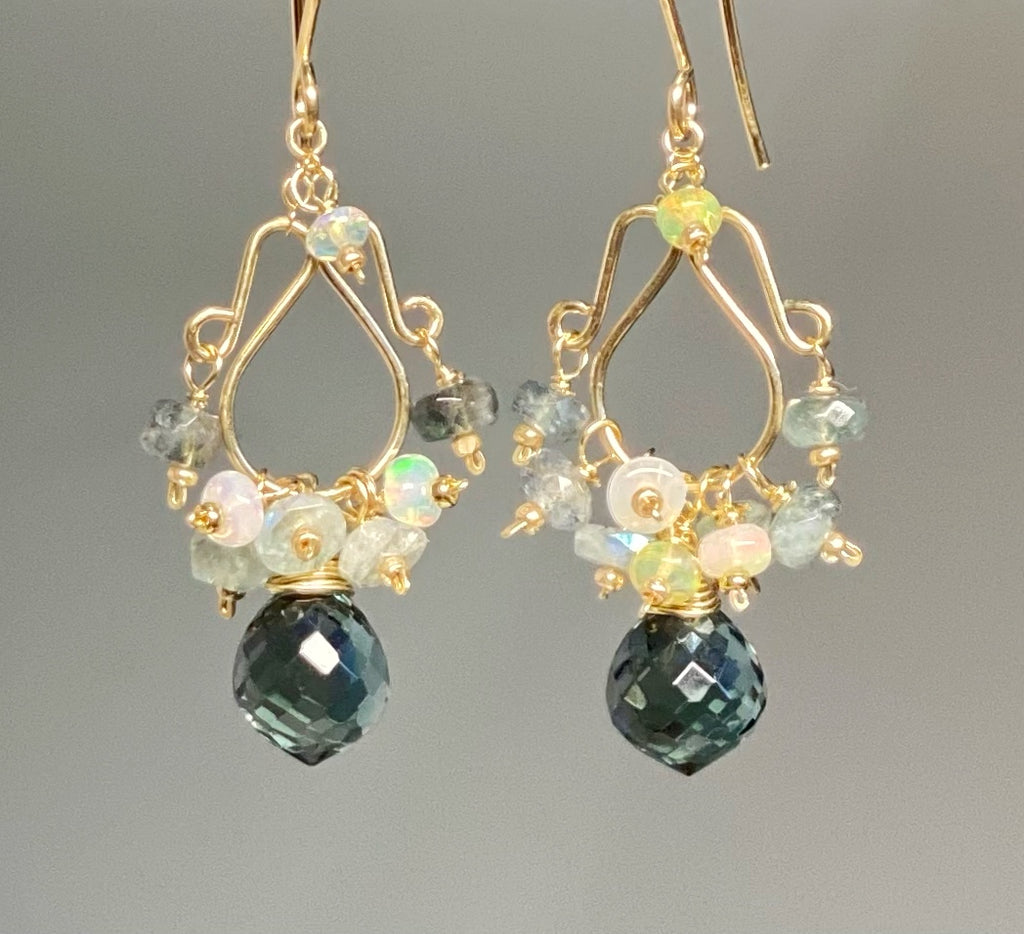 Rose gold chandelier earrings with aquamarine and opal dangling against grey background