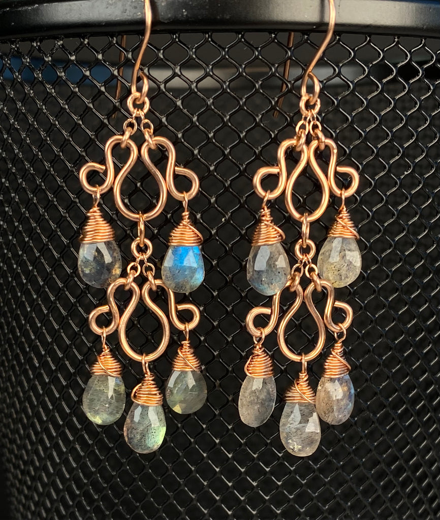 Two-tier rose gold-filled chandelier earrings hanging against black metal mesh, with faceted labradorite drops.
