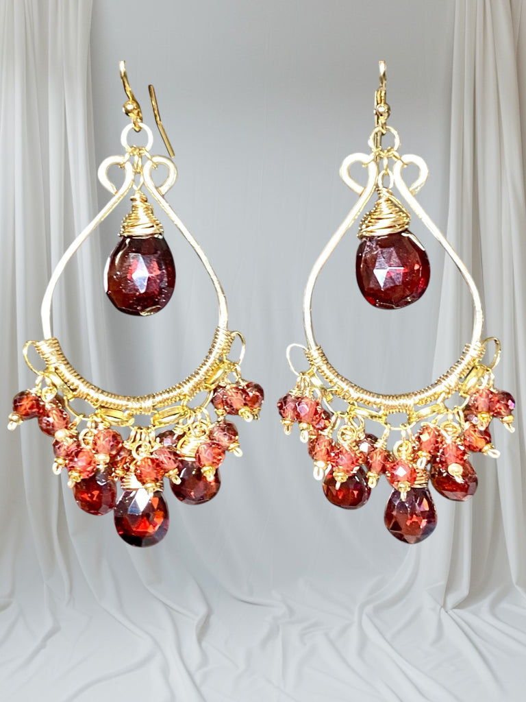 Red garnet chandelier earrings 14kt gold fill dangling in front of pleated off white drapes
