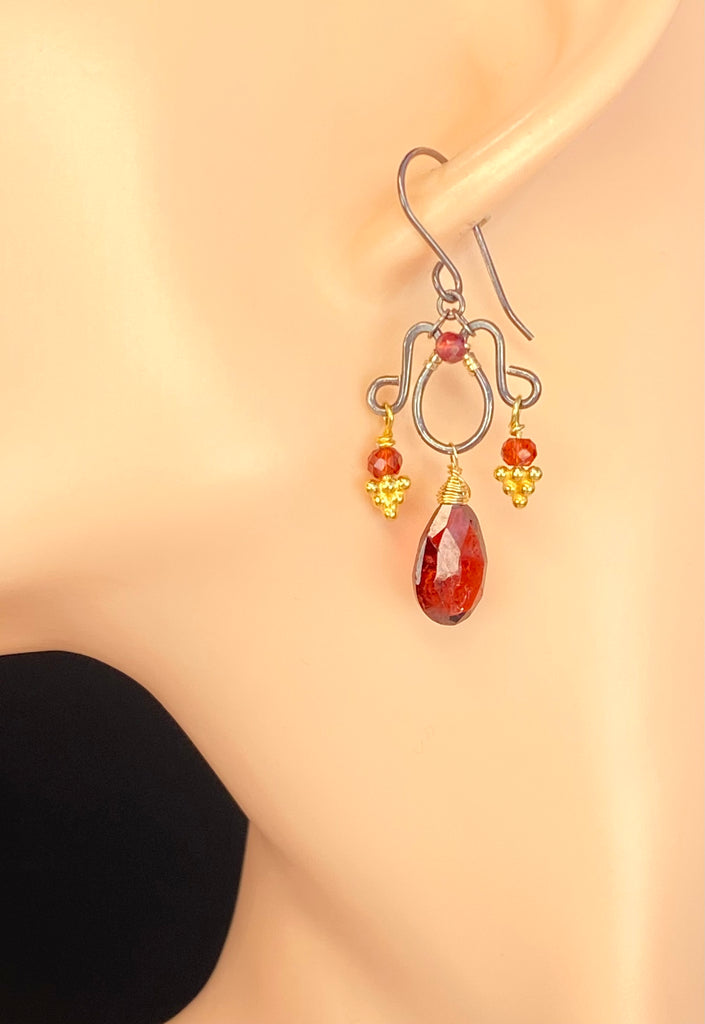 Red garnet chandelier earring shown on a mannequin ear, with an oxidized silver French hook, garnet pear drop, and gold vermeil accents.