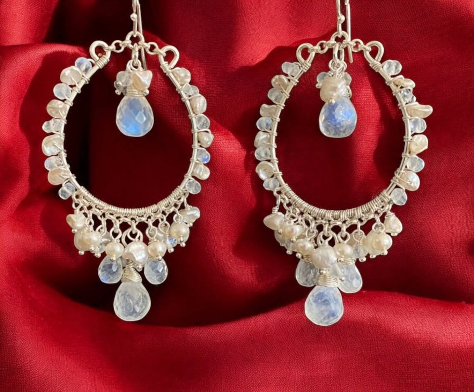 Ornate hoop earrings with gemstones on a red fabric background

