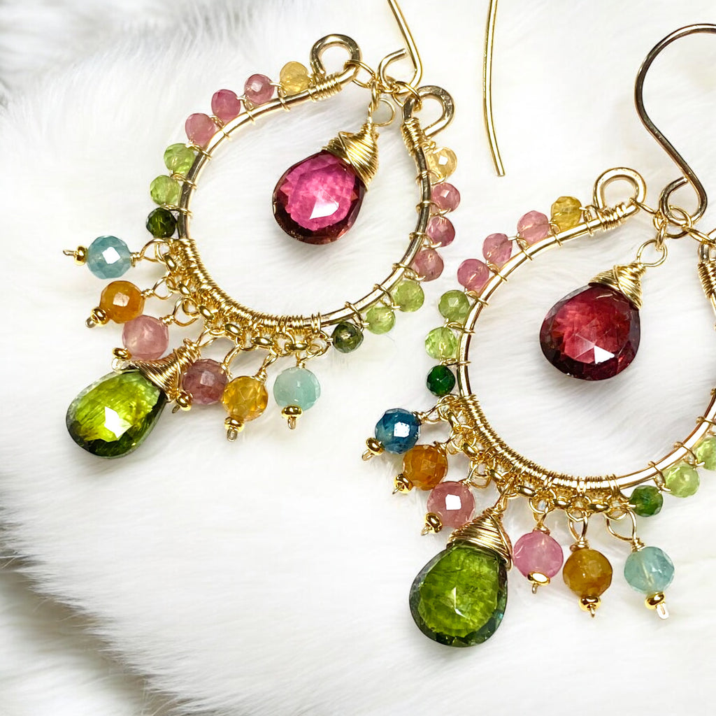 Multicolor tourmaline chandelier hoop earrings gold fill lying on white furry fabric