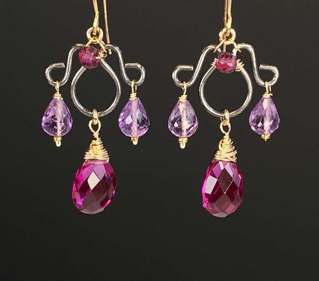 Mixed-metal chandelier earrings with violet rhodolite pear drops, lavender amethyst teardrops and mystic garnet accents against black.
