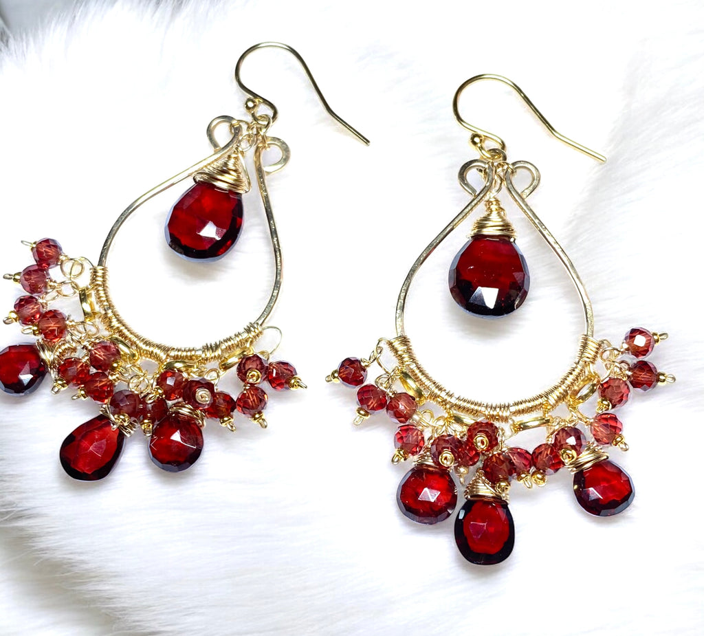 Red garnet chandelier earrings 14kt gold fill lying on white fabric background