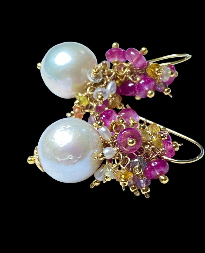 Pearl and pink sapphire cluster earrings gold lying on black background - flat lay product shot