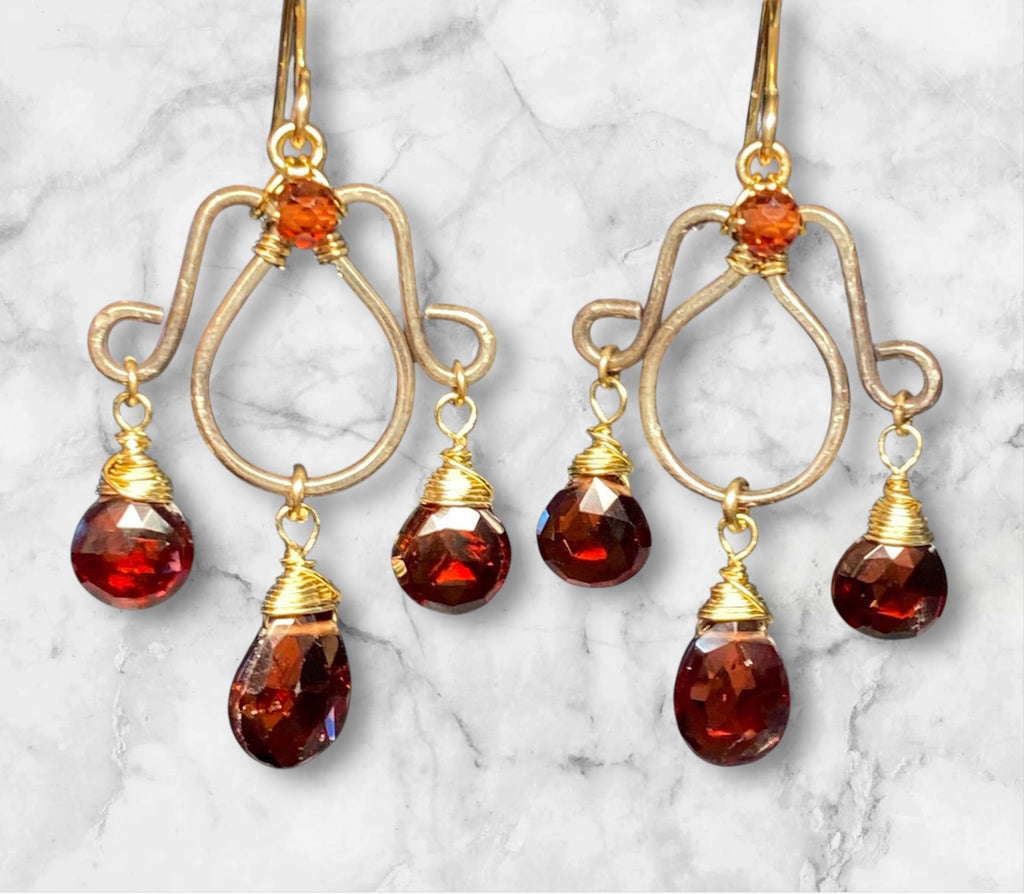 Oxidized silver chandelier earrings dangling red garnet faceted briolettes wire wrapped in 14kt gold fill wires shown in front of grey mottled marble slab