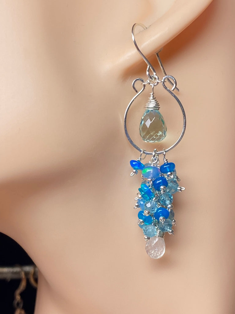 Sterling silver chandelier Earring with blue and aqua and white gemstones on a mannequin ear.