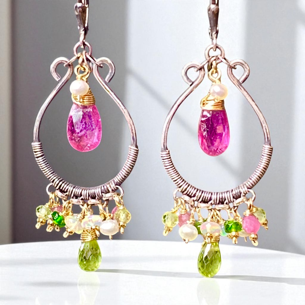 Pair of hoop earrings with colorful gemstones on a white surface.