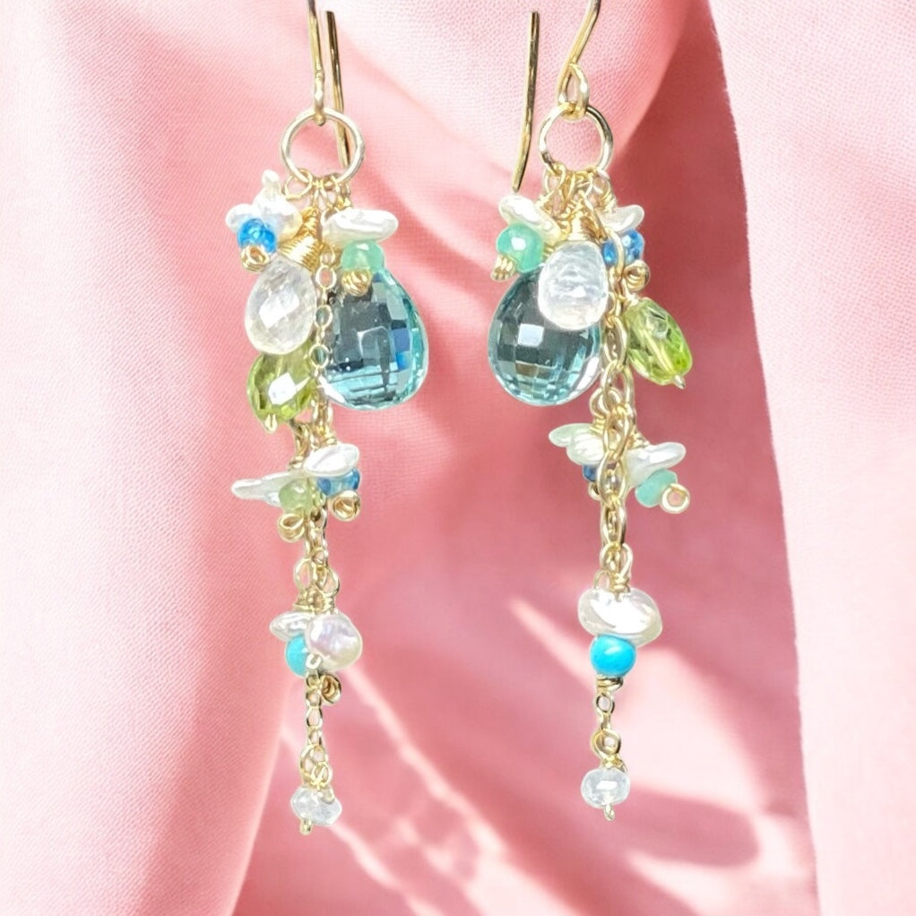 Delicate earrings with colorful beads on a pink fabric background