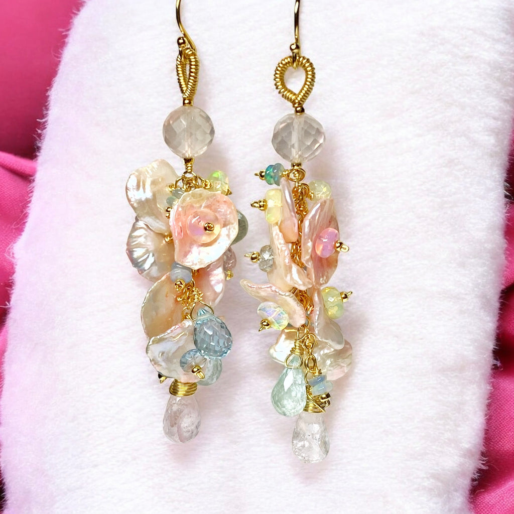 Earrings dangling infront of furry white fabric in front of pink fabric.