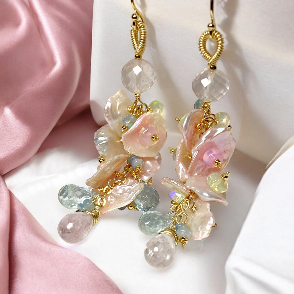   Earrings dangling on white fabric infront of pink fabric.